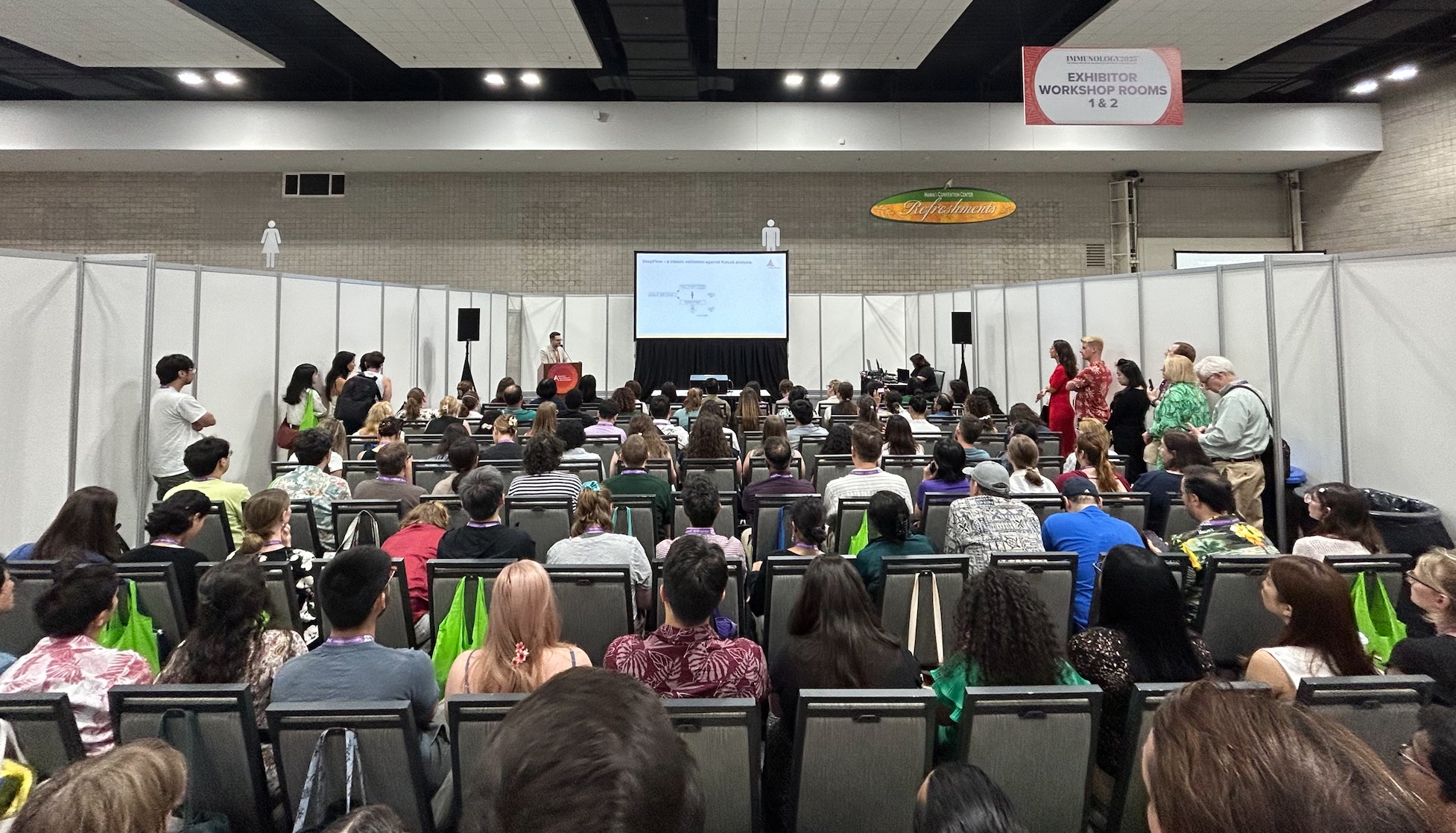 Full session room viewed from the back, workshop signage overhead